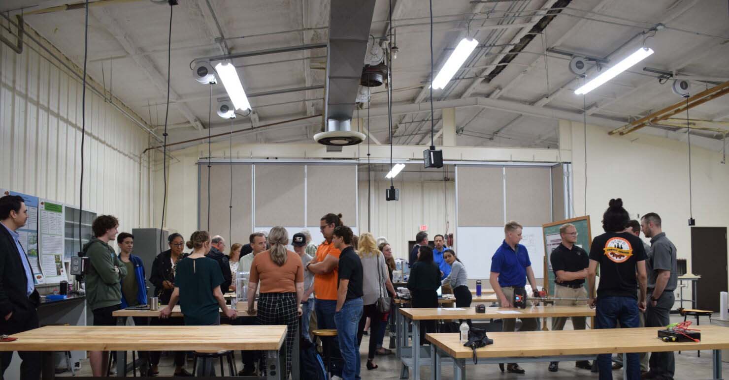 Students and faculty gathered around tables in a classroom for the ABET program.