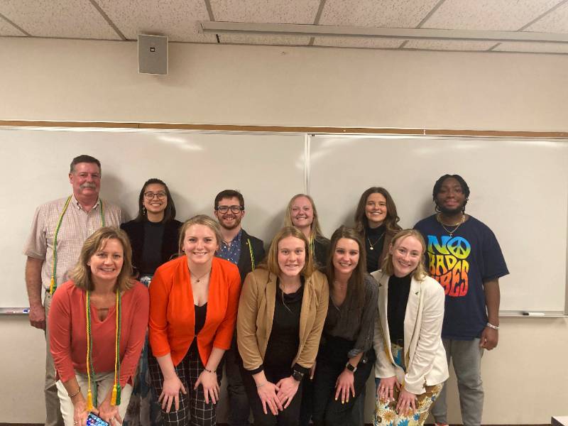 Students and advisors standing in front of white board in a classroom.