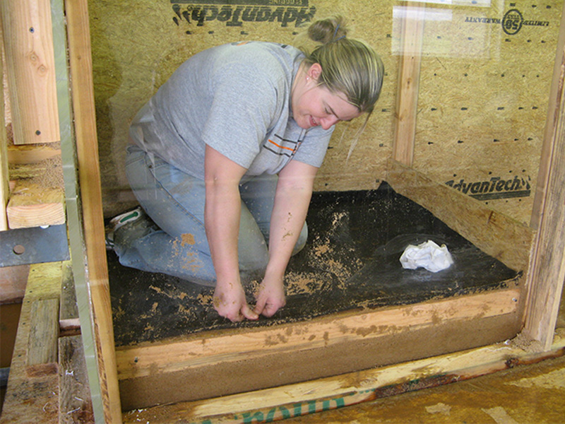 Student tamping down dirt at the bottom of her senior design project.