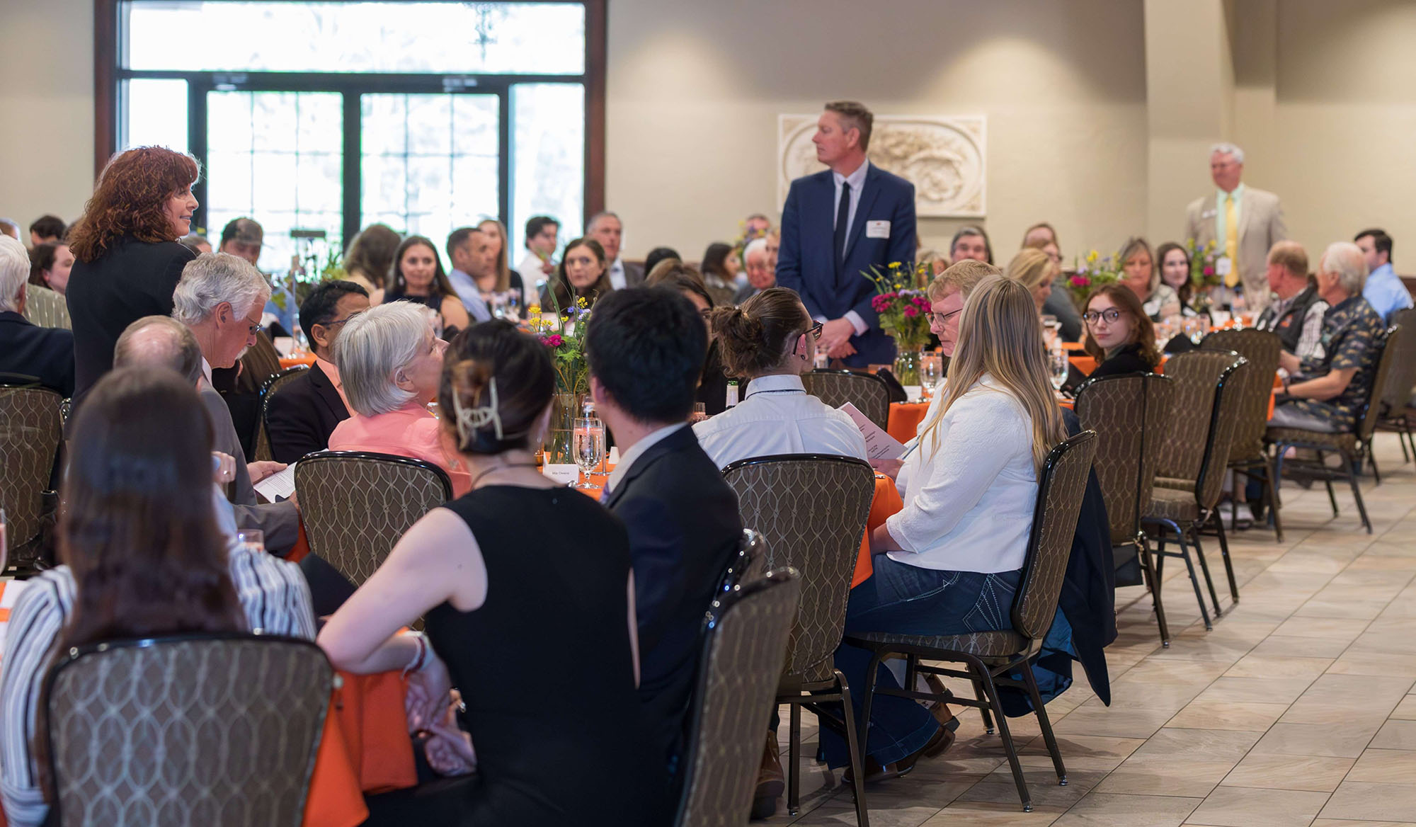 Everyone sitting down at the banquet except three people are standing for recognition.