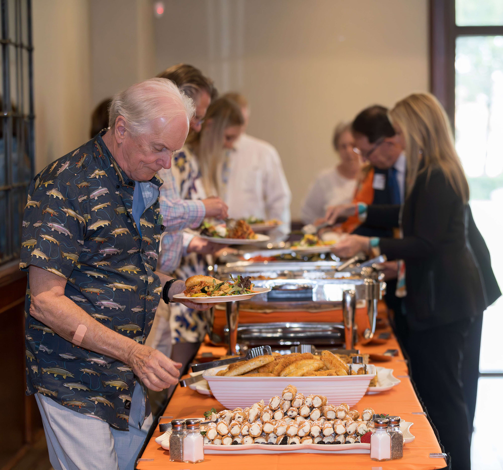 A gentleman getting food in a buffet line.