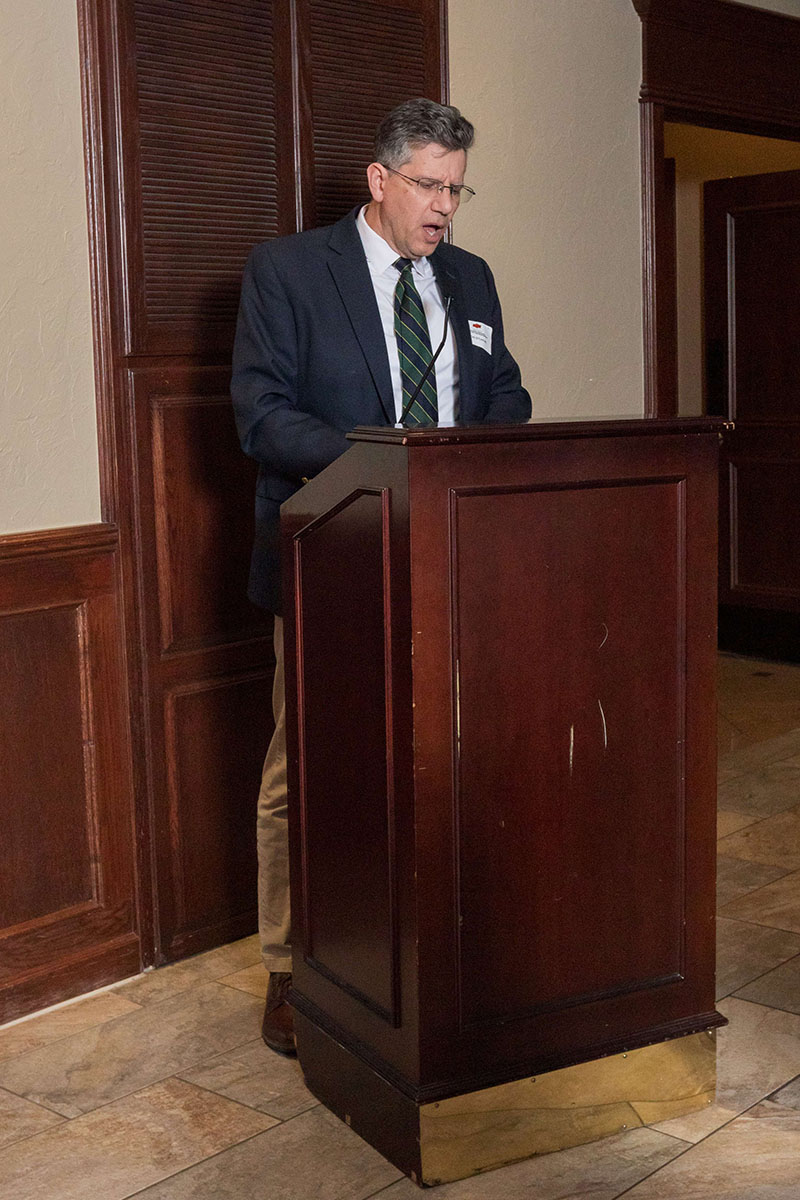 Timothy O'Connell standing behind a podium giving a speech.