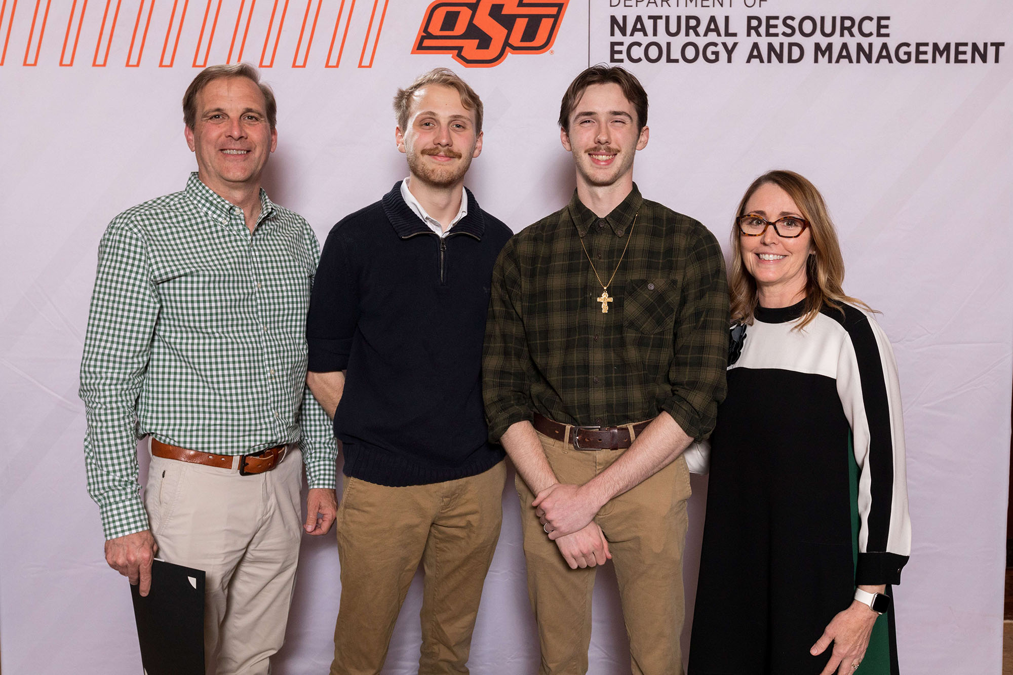 Four people posing in front of a white banner.
