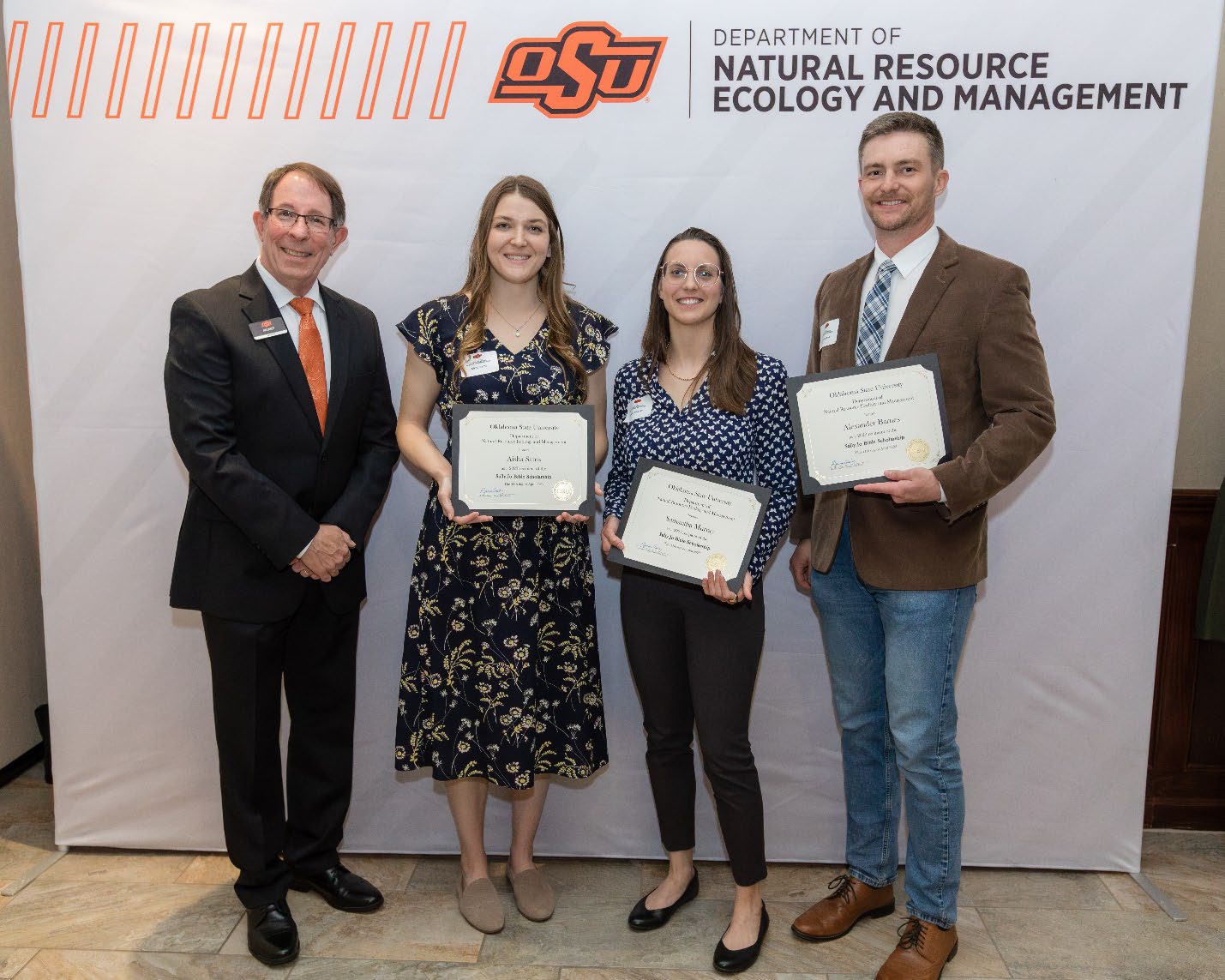 Jim Ansley next to Aisha, Samantha and Alex accepting their Graduate Student Scholarship award.