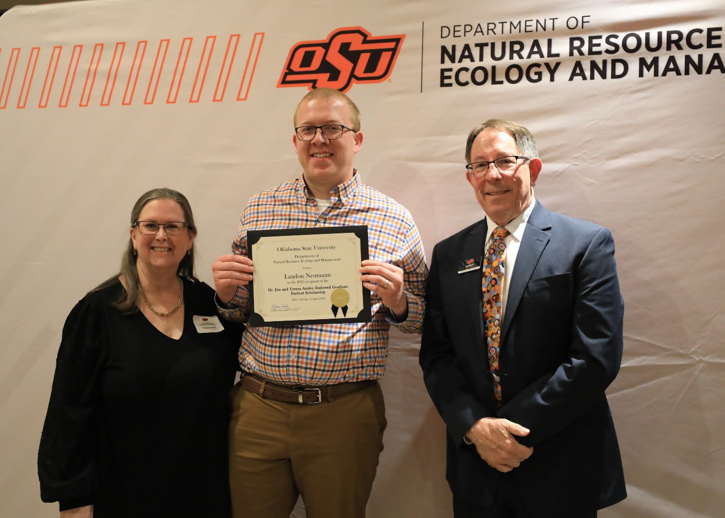Landon Neumann holding his award next to Dr. Jim and Teresa Ansley.