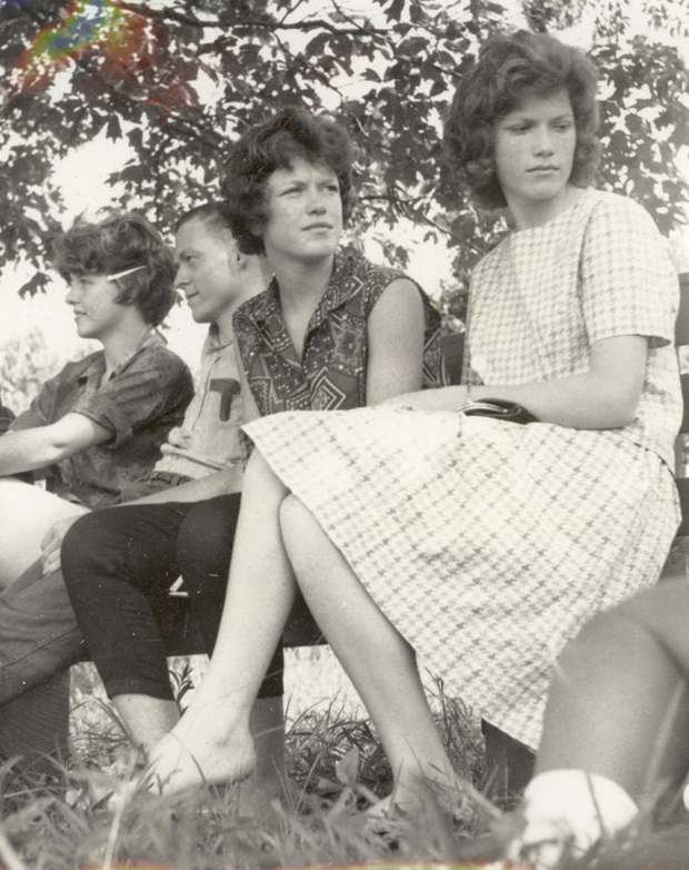 A group of people are sitting down in chairs in the grass in a row.