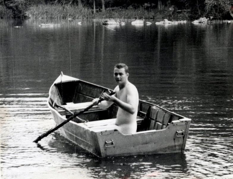 A man with a paddle in his hands sits on a boat on the water.