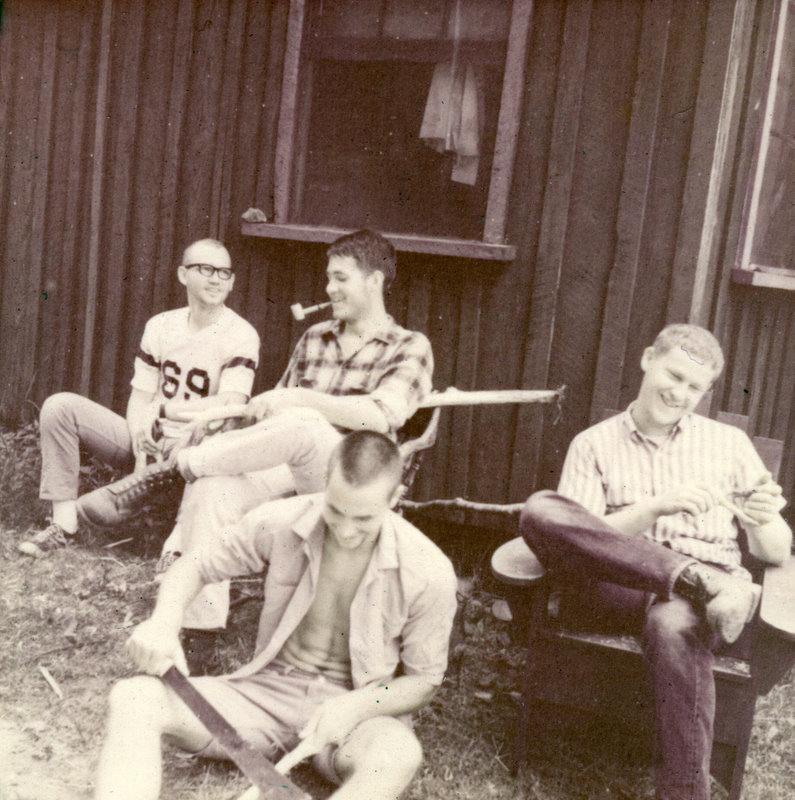 Four students sitting outside laughing.