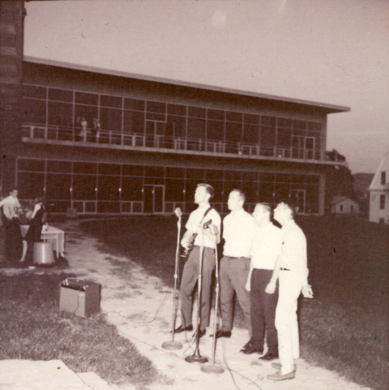 A group of people outside speaking at a microphone.