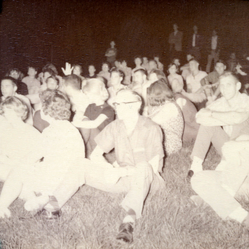 A group of people sitting in grass.