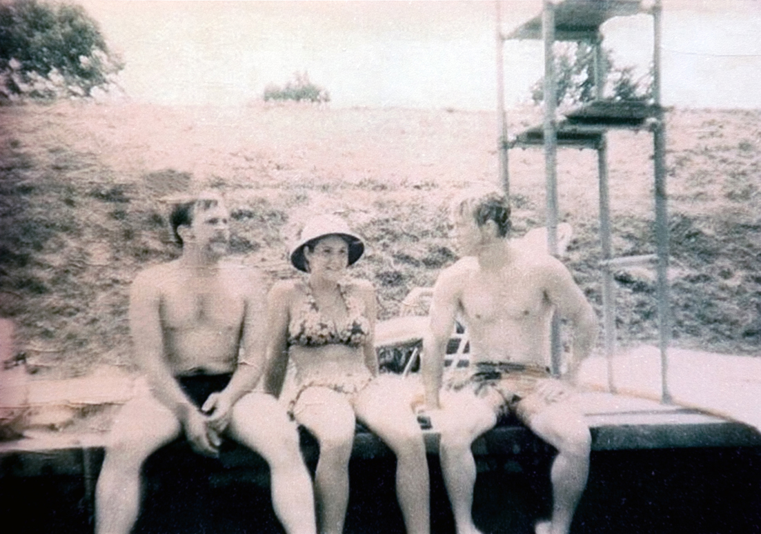 Three students sitting outside in their swimming outfits.
