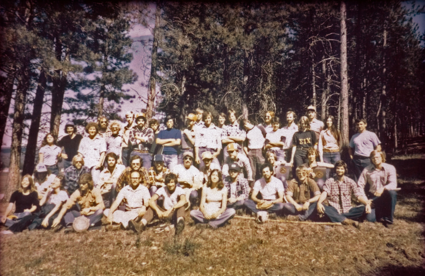 A large group of students sitting outside on grass.