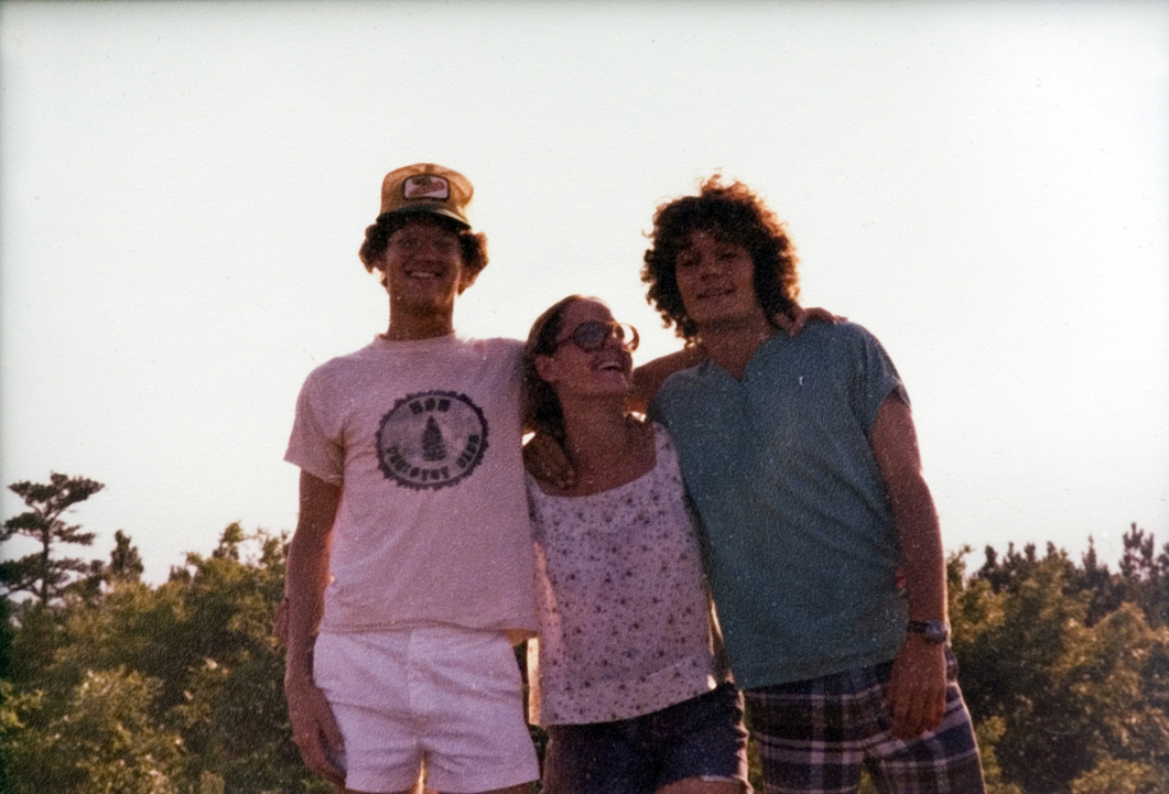 Three peope standing together outside, smiling for the camera.