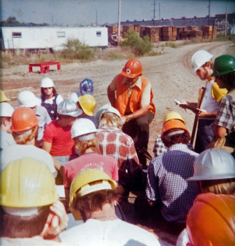 A group of people outside wearing hardhats.