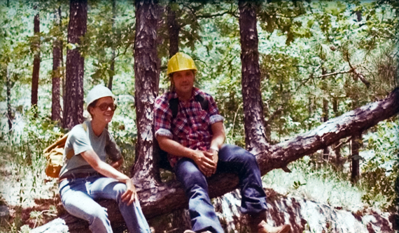 Two students sitting on a cut down tree.