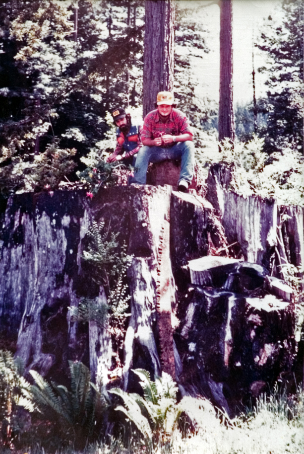 Two students seated atop a rock formation pose for a photo.
