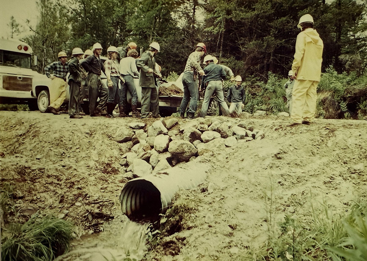 A group of people with shovels preparing the road for water drainage.
