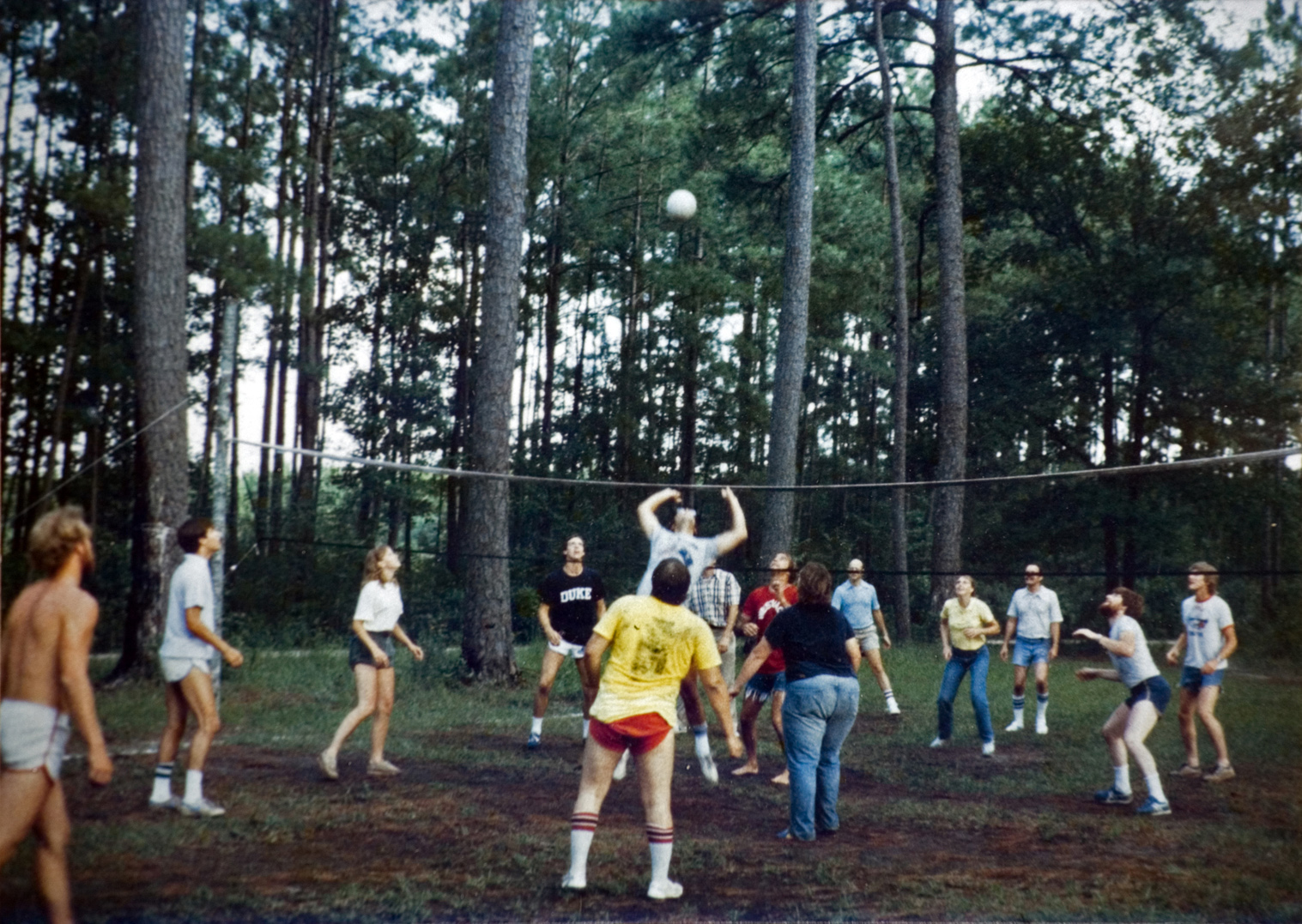 A group of people playing volleyball outside.