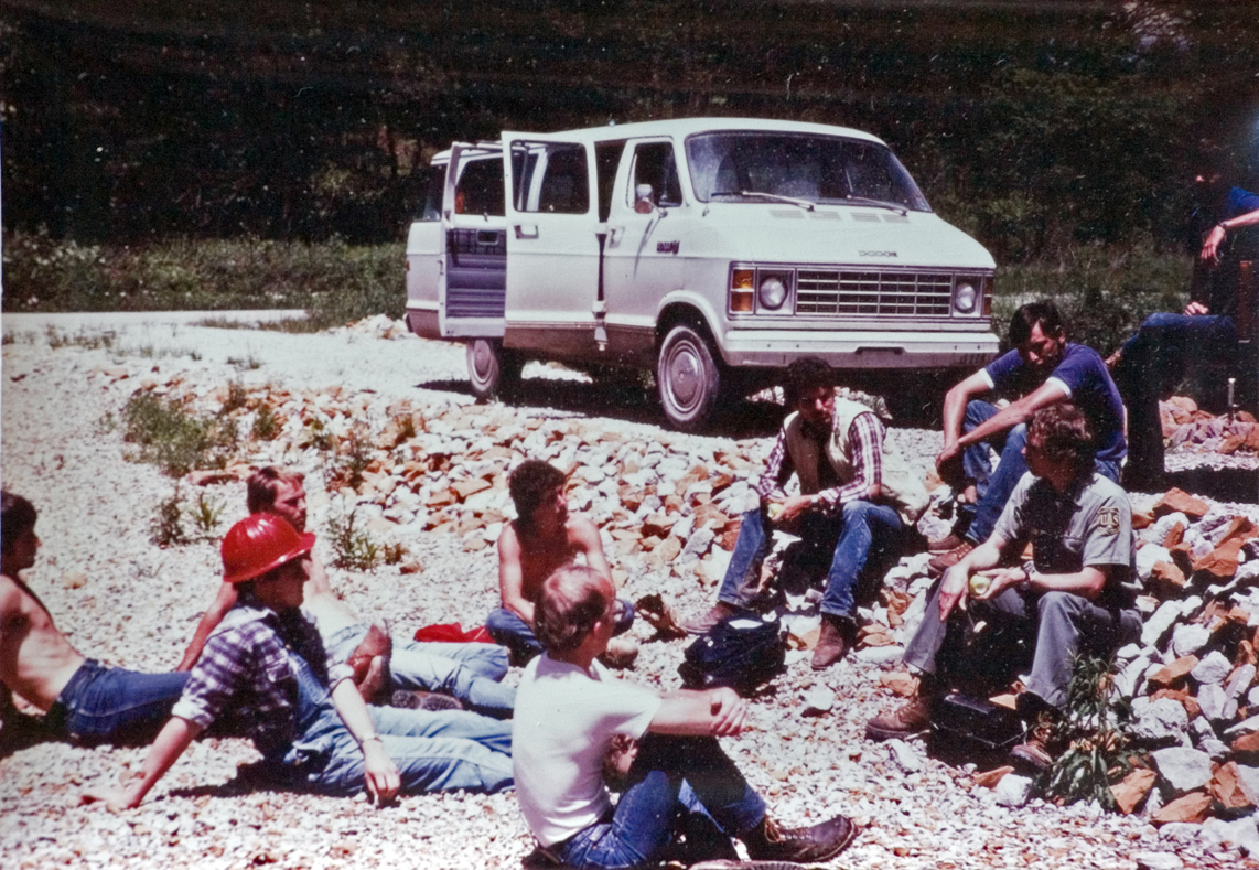 The group takes a break outside the van on the rocks.
