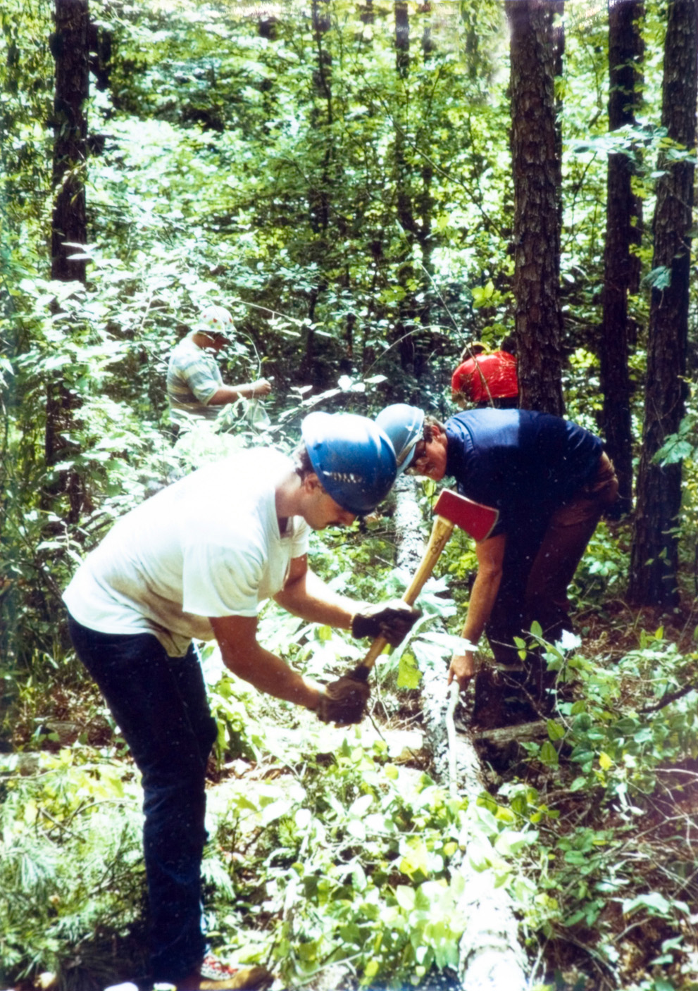 Two students go to work cutting a log with axes.