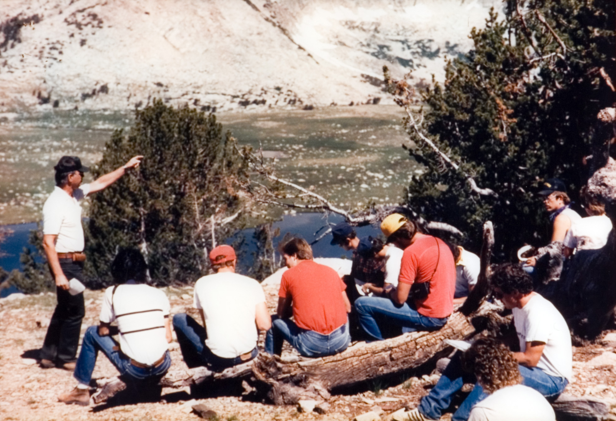 Students seated outside as they receive instruction overlooking a valley and another mountain.