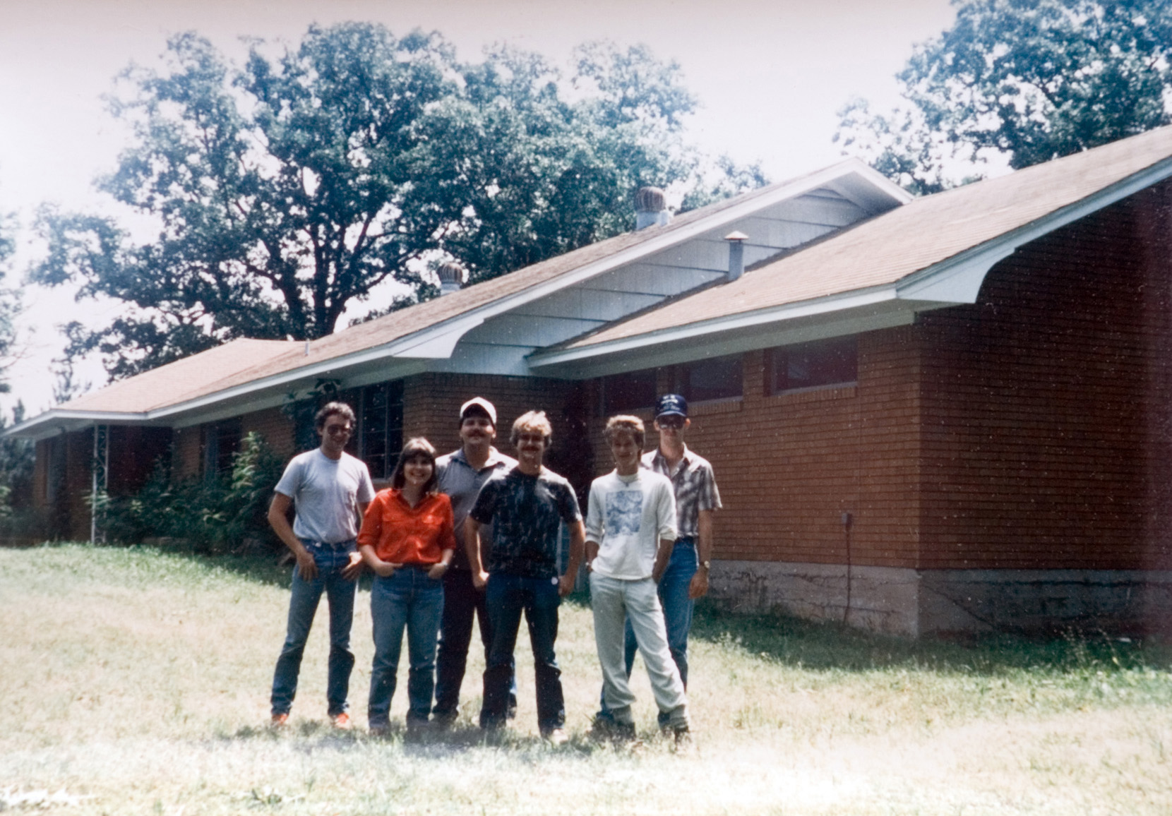 Instructors and four students pose for an outdoor photo outside of a house.