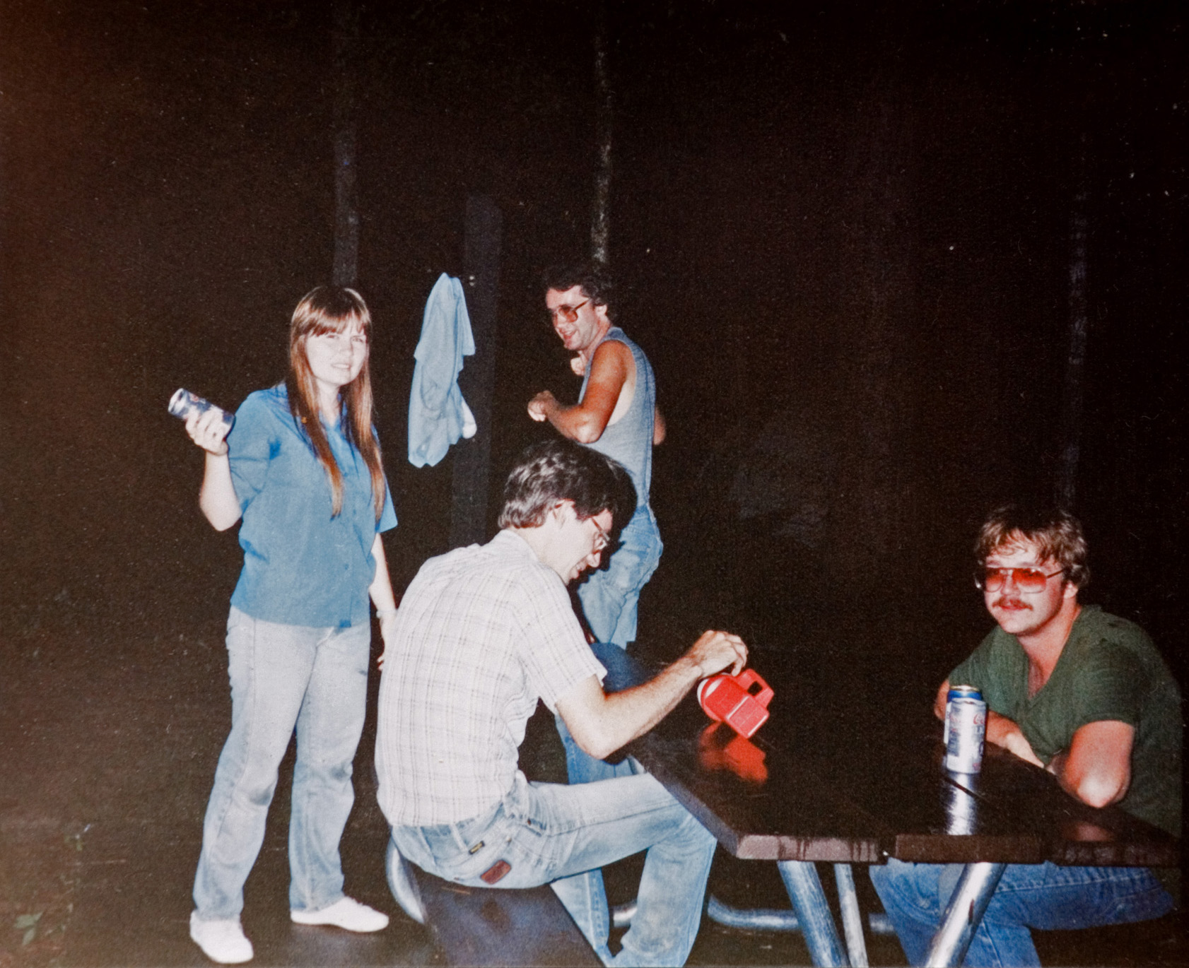 Four students hanging out with one anothet at the campsite during the night.