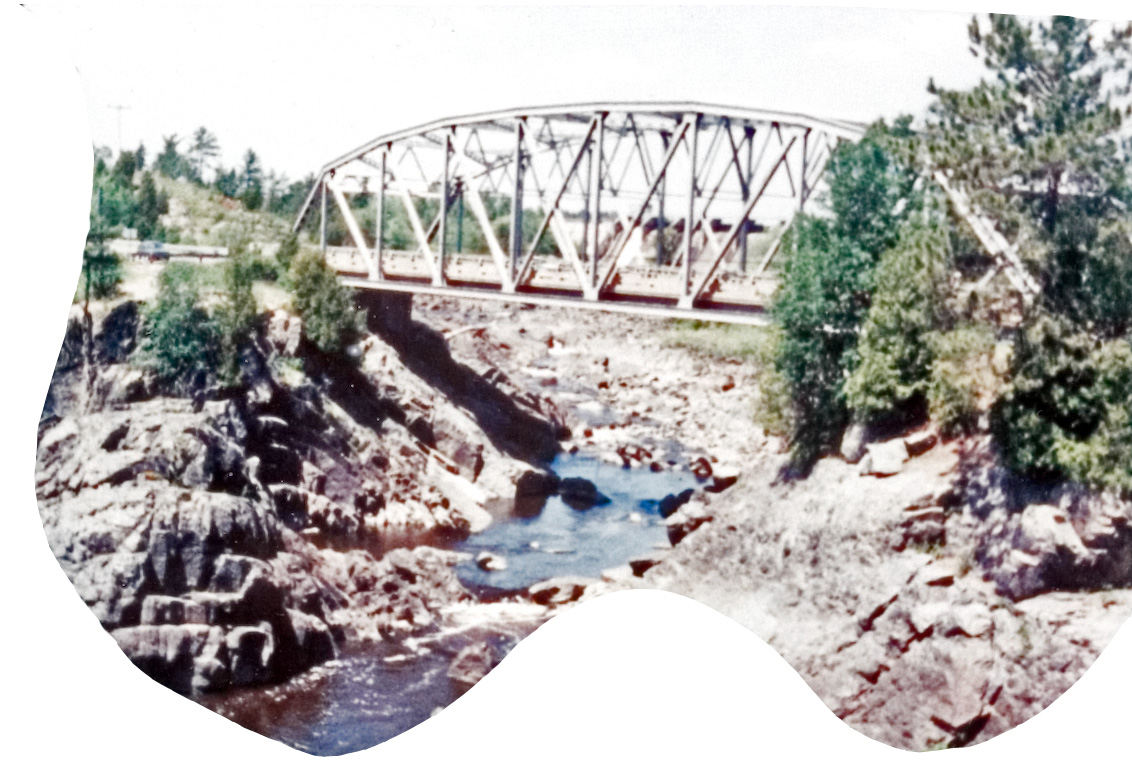 A wooden bridge over a rocky hill next to a stream of water.