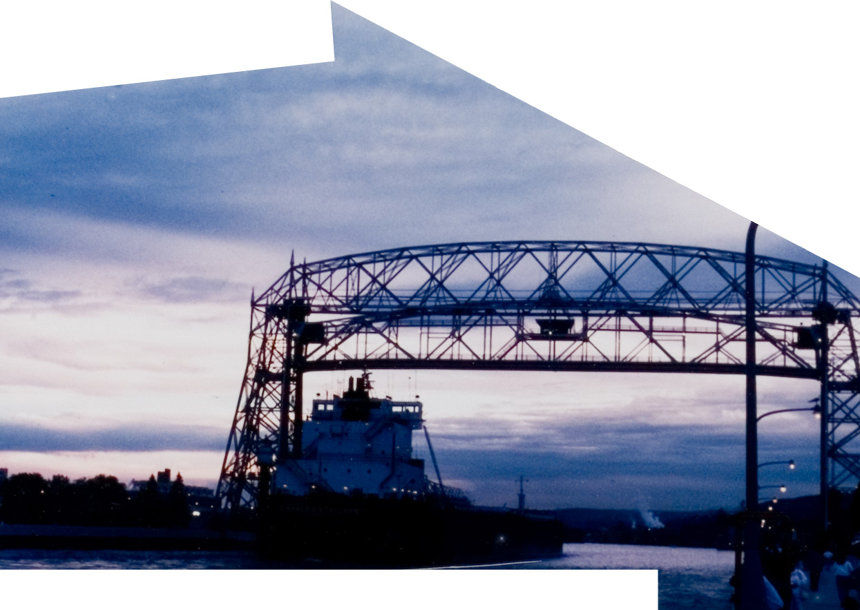 A scenic view of a blue sky with a boat passing by a metal structure in thr water.