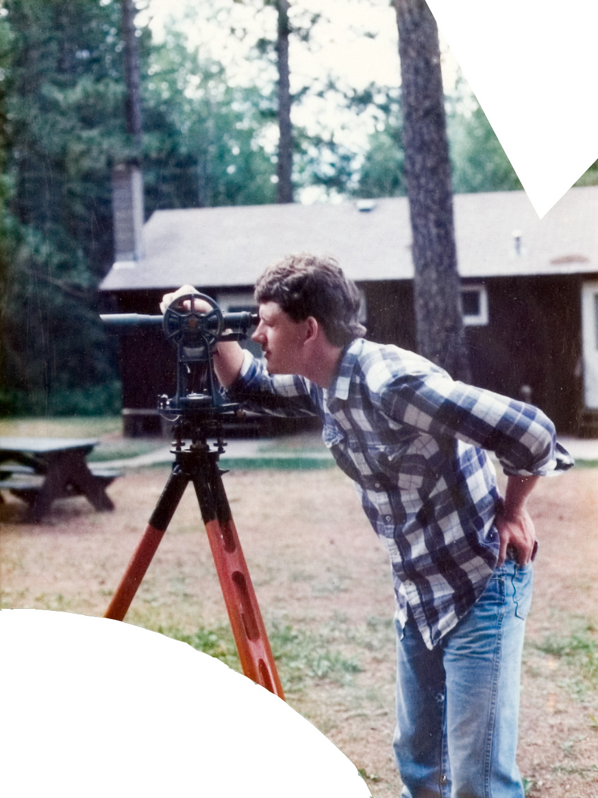 A student in a plaid shirt using a measuring tool outside.