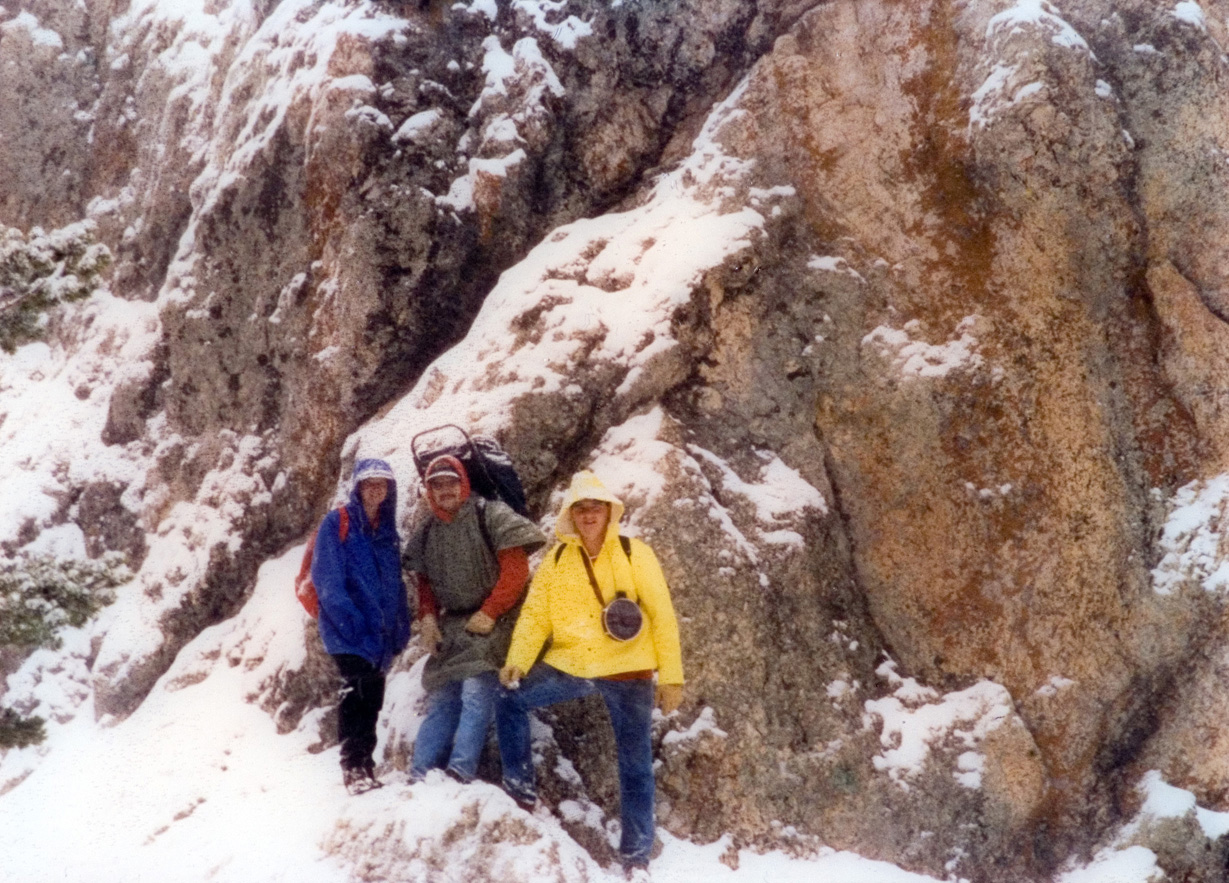 Three students stop on hike on a snowy mountainside for a photo.