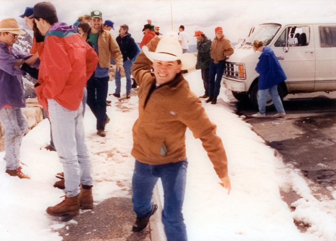 Students gather in the snow as one student winds up for a snowball throw.