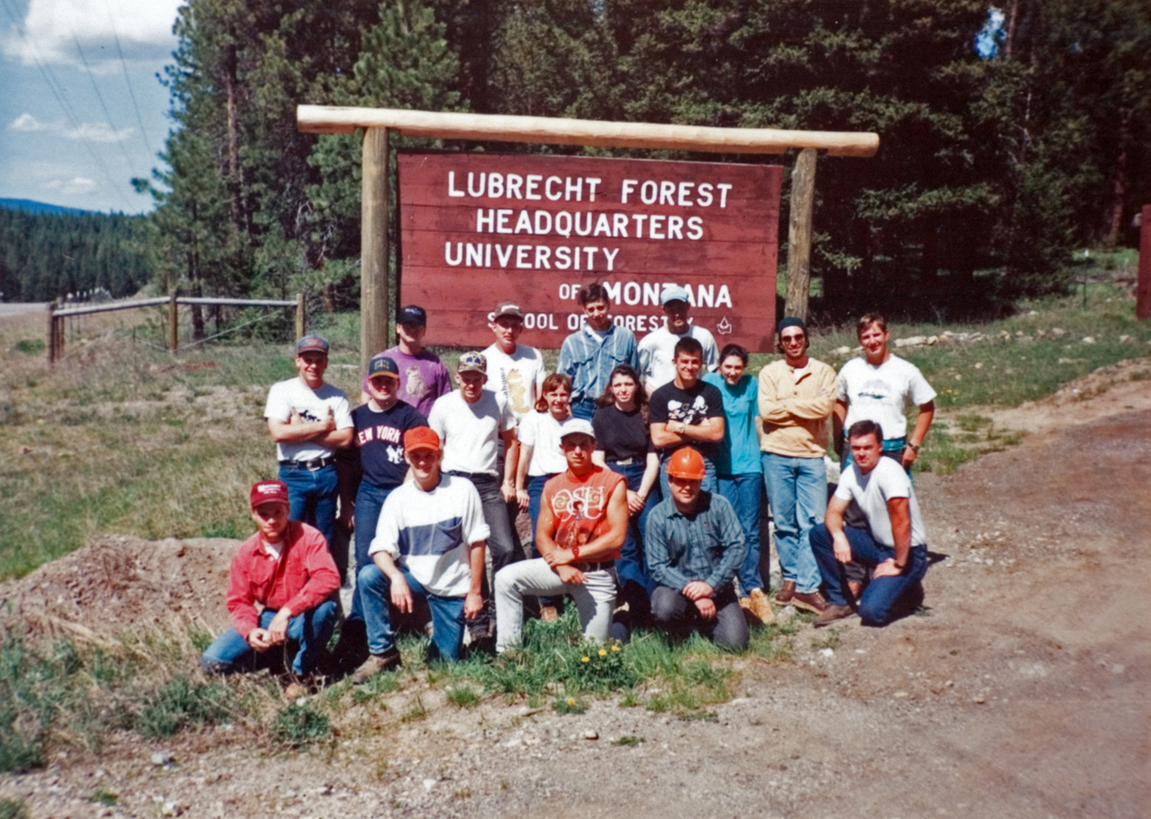 A group of students posing of a photo next to an outdoor sign.