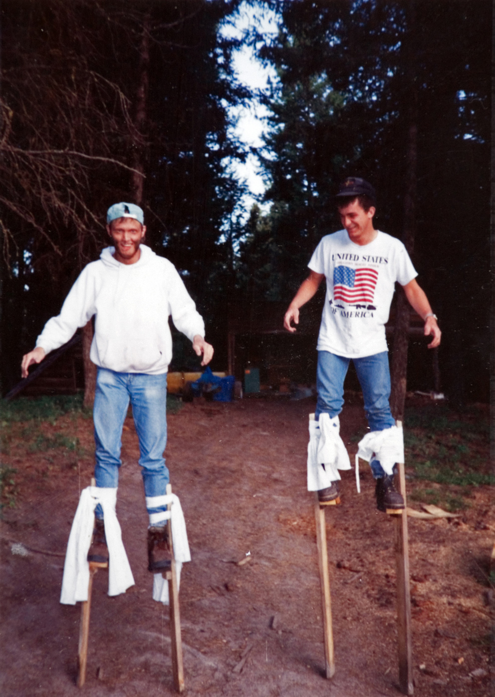 Two people walking outside on stilts.