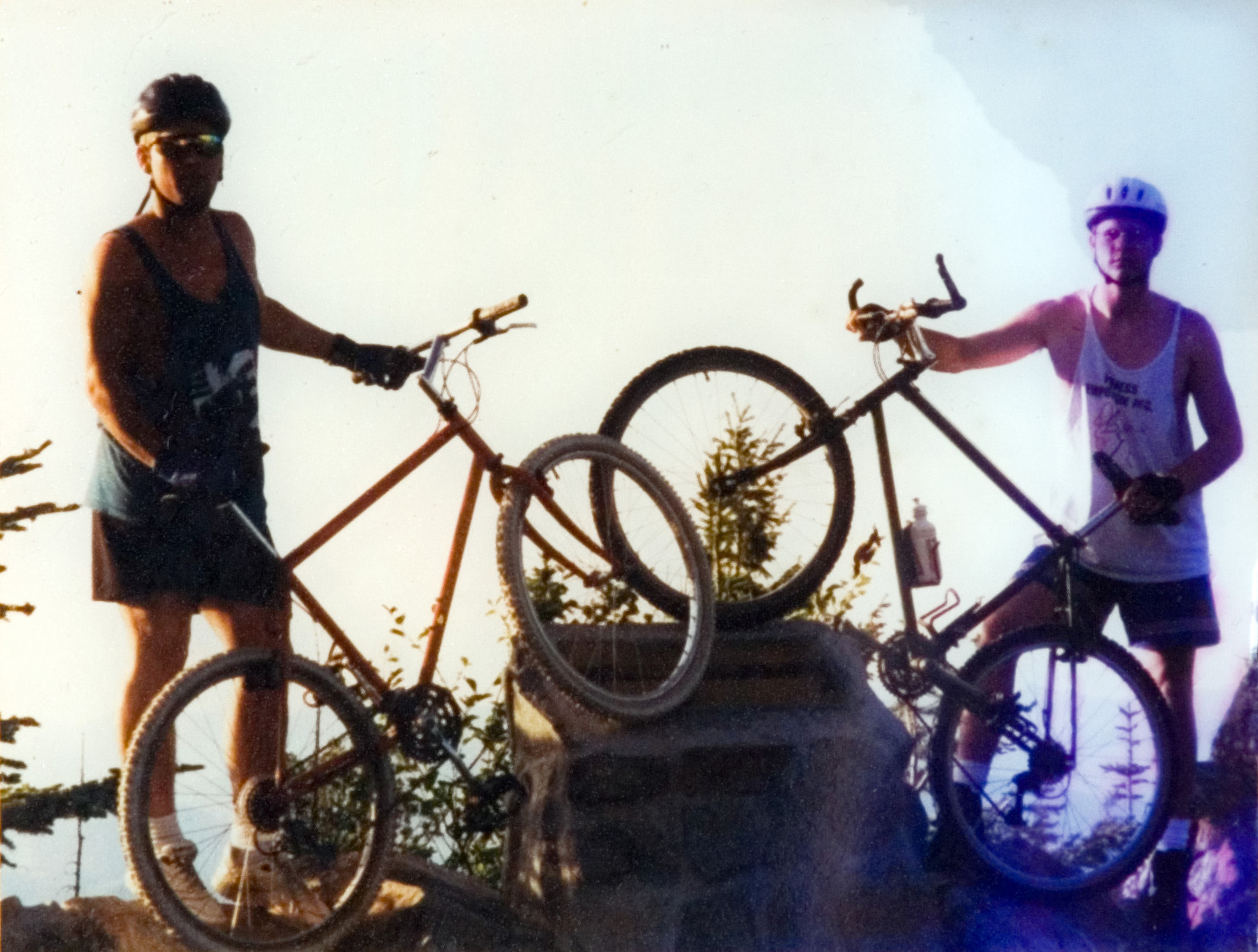 Two students in helmets standing next to their bicycles at a trail marker to pose for a photo.