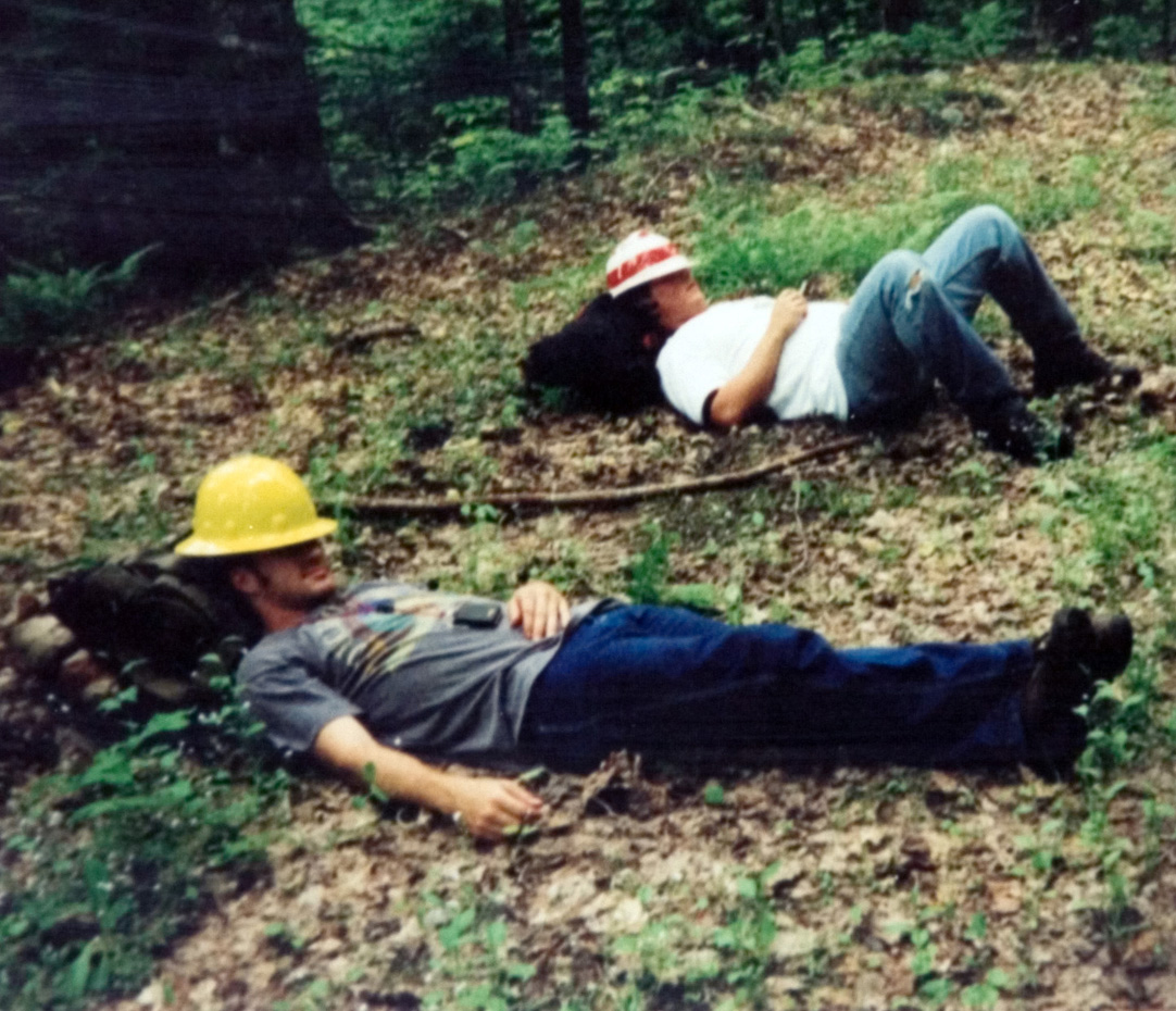 Two students laying down as they rest with hardhats covering their faces.