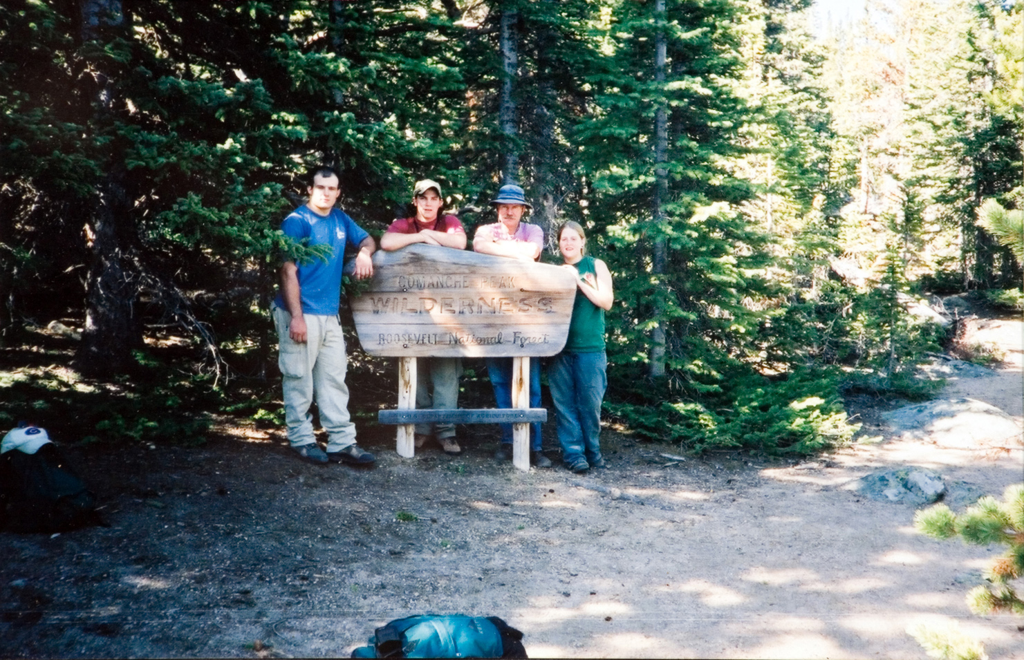 Four individuals standing behind a sign that says "Comanche Peak Wilderness".