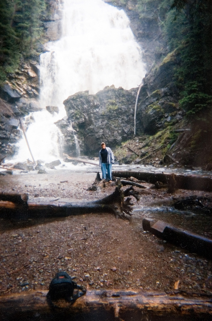 A student posing for a photo at the bottom of a waterfall.