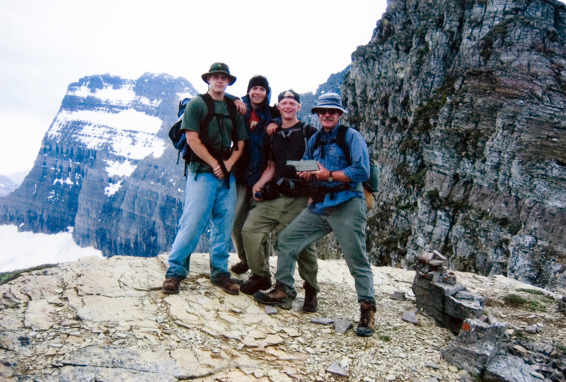 Four students posing for a photo on a mountain trail.