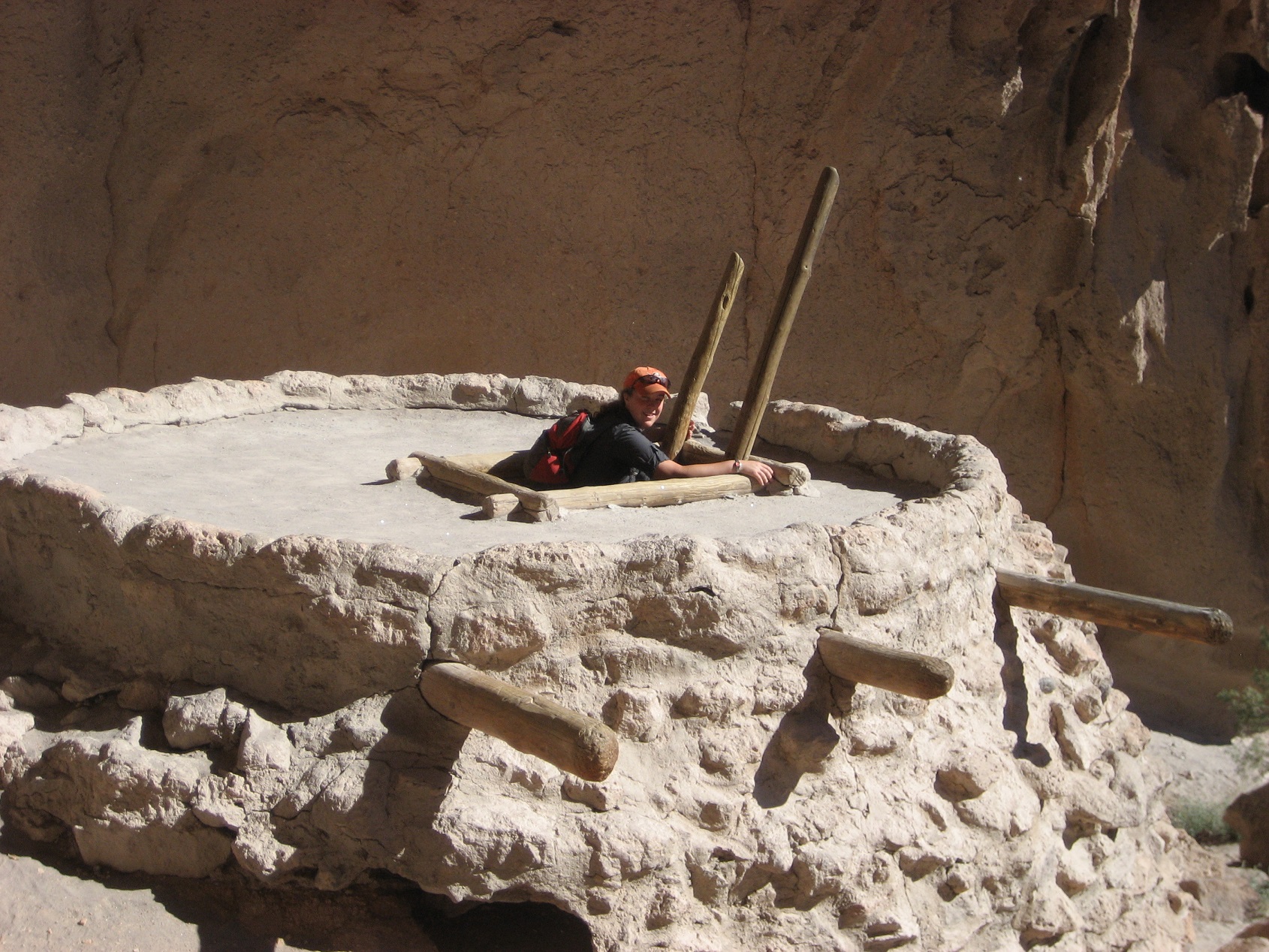 A student climbing ladder out of the top of a rock formation
