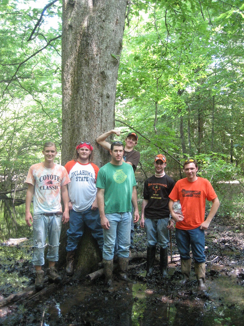 Participants are standing in front of a tree in the forest.