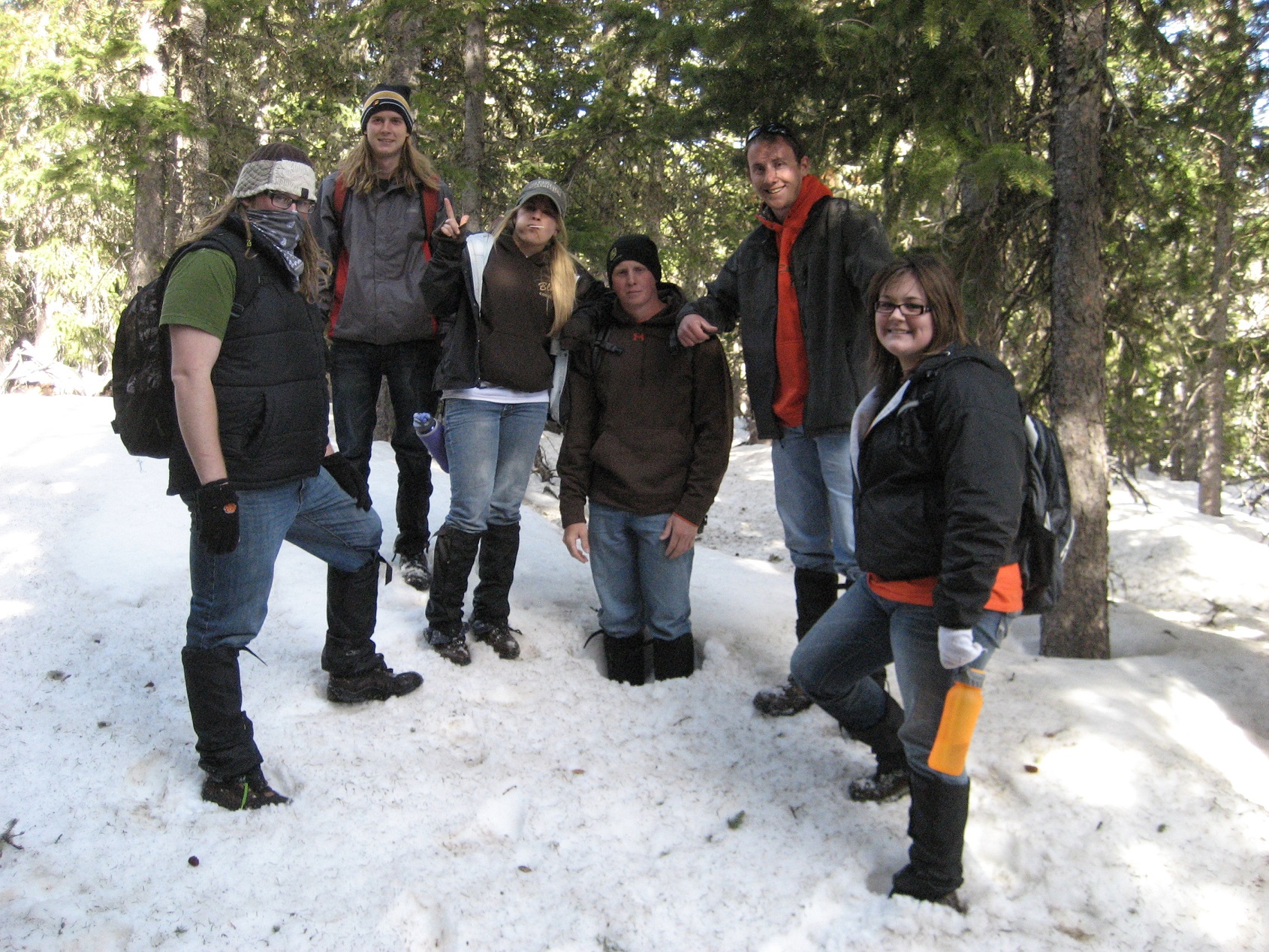 A group of students standing in the snow in the woods.