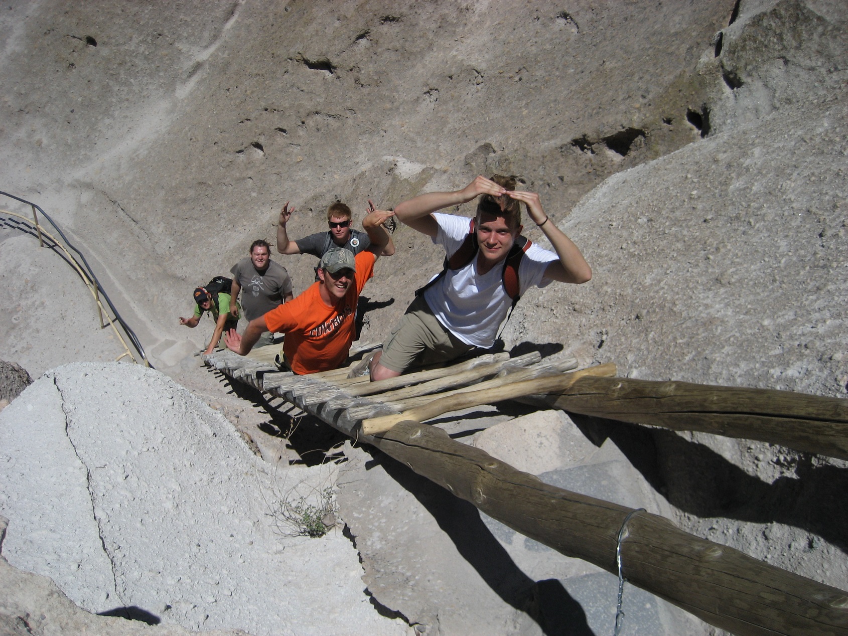A group of participants climbing a ladder going up the side of a steep mountain made of rock.