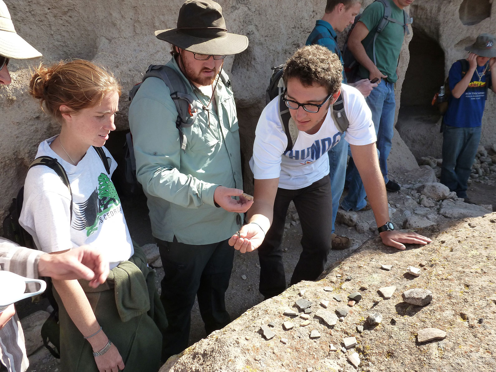 A group of participants looking at a collection on little rocks laid out across one big rock.