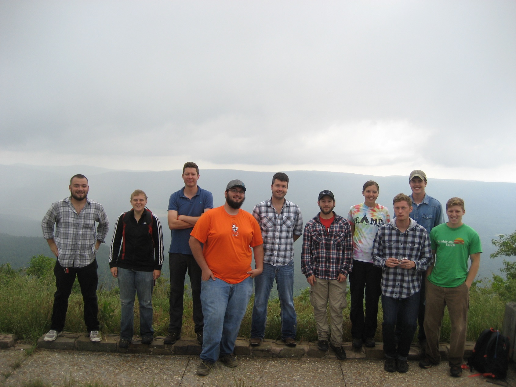Ten individuals standing at on overlook for a group photo.