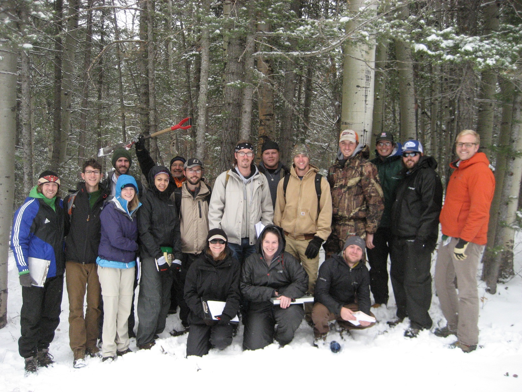 Several participants standing in the snow in a wooded area.