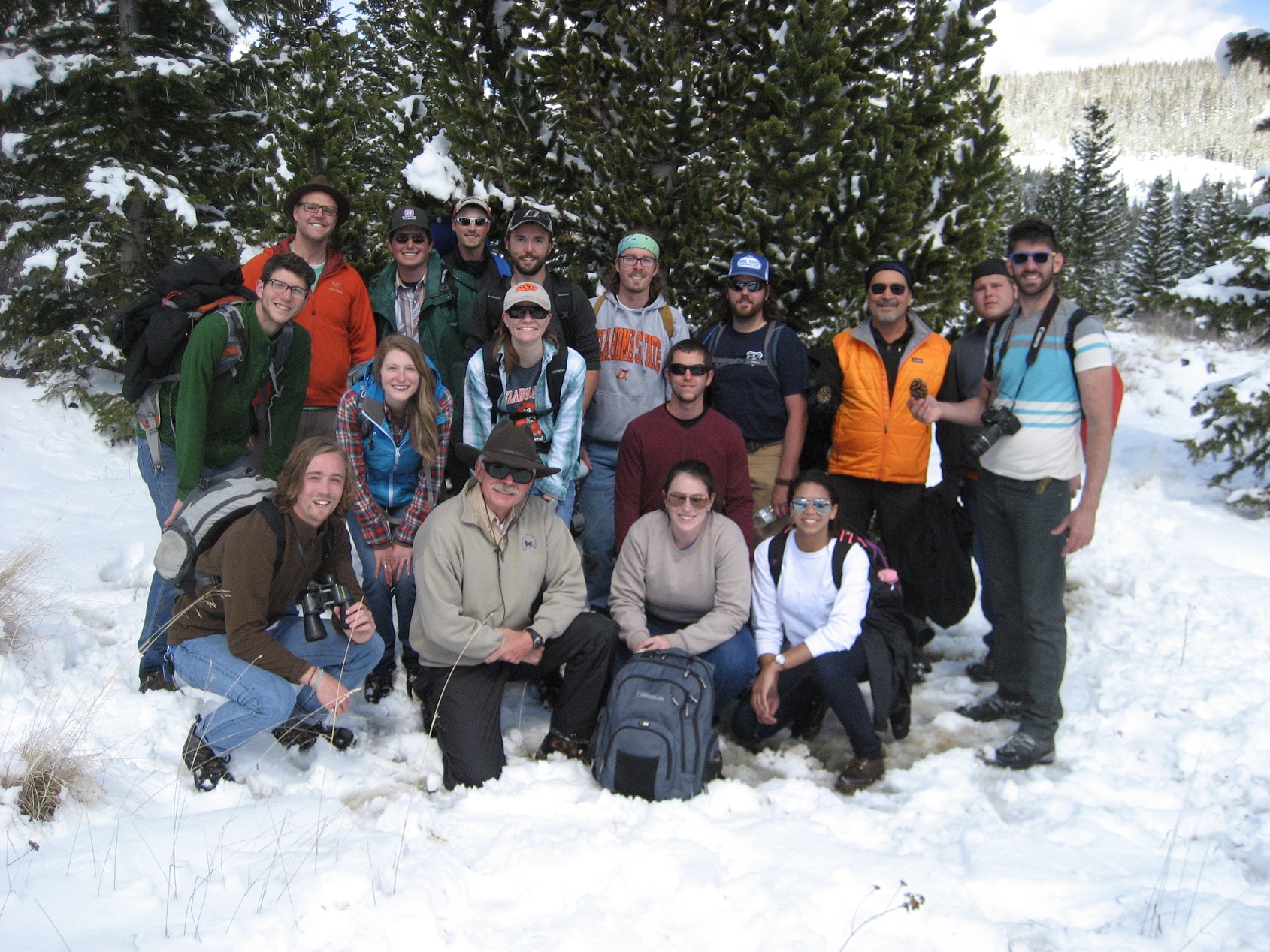 Several participants standing in the snow in a wooded area.
