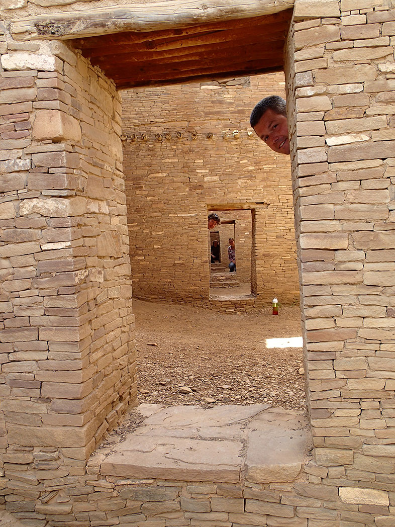 A person stinking their head out from a window built into a stone wall.