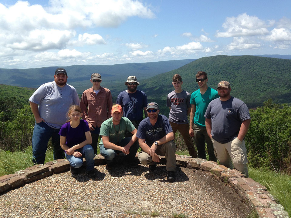 A group photo of nine people overlooking a mountain range.