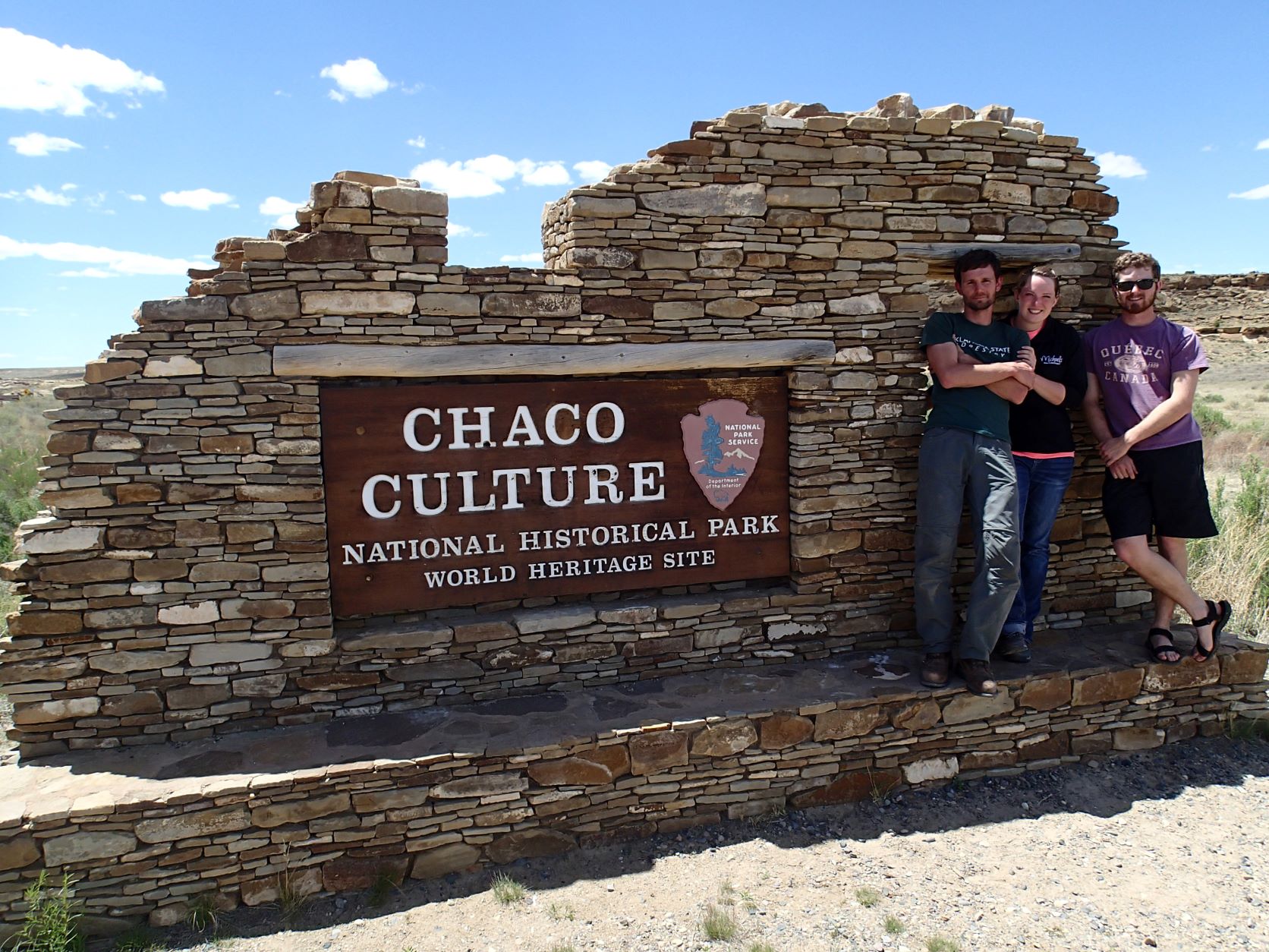 Three people posing infront of a "Chaco Culture" stone sign.